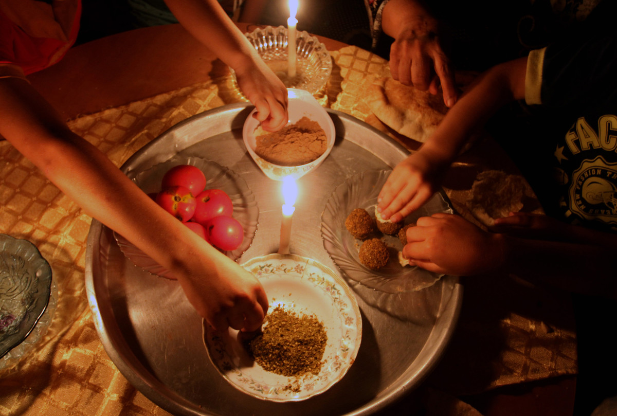 28 Julai - Sebuah keluarga di Rafah, Gaza terpaksa menggunakan lilin ketika malkan malam kerana bekalan elektrik terputus. Kebanyakan rumah di Gaza mendapat bekalan elektrik hanya beberapa jam dalam sehari.