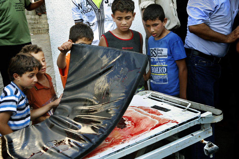 28 Julai - Kanak-kanak di luar rumah mayat di Hospital al-Shifa melihat tumpahan darah dari salah seorang mangsa yang dibawa ke hospital tersebut.