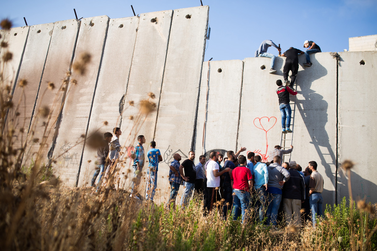 3 Julai - Beberapa penduduk Palestin memanjat tembok pemisah Zionis di pekan al-Ram di kawasan Al-Quds dalam usaha mereka untuk mendirikan solat di Masjid al-Aqsa pada hari ketiga Ramadan.